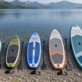Varias tablas de paddle surf de distintos largos y anchos alineadas junto a un lago